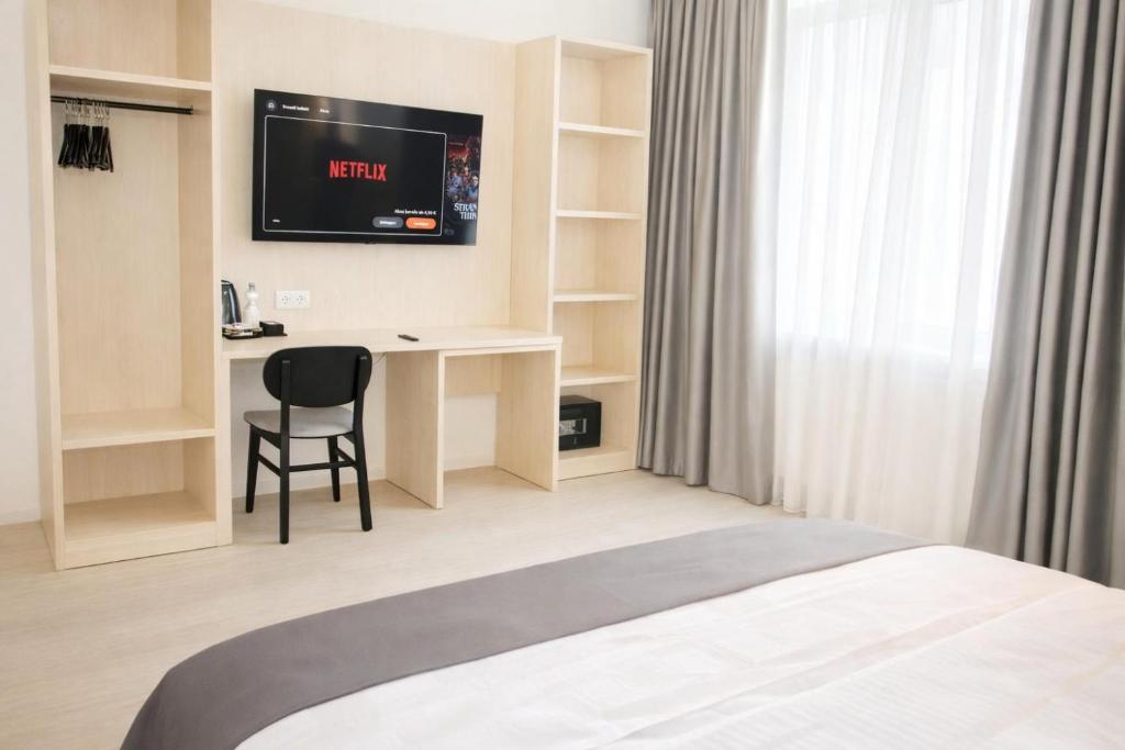 ein Hotelzimmer mit einem Bett, einem Schreibtisch und einem Fernseher in der Unterkunft Niko Hotel am Hannover Hbf in Hannover