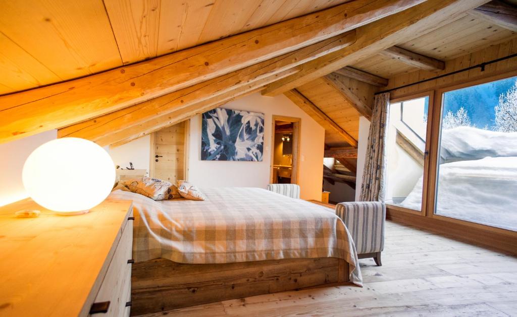 ein Schlafzimmer mit einem Bett und einem großen Fenster in der Unterkunft Chesa Chamuera in La Punt-Chamues-ch