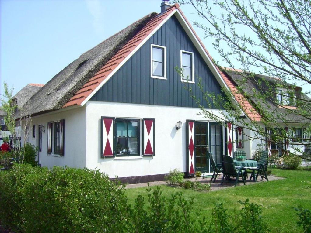 a house with a gambrel roof with red and white windows at Villa Julia 148 in Callantsoog