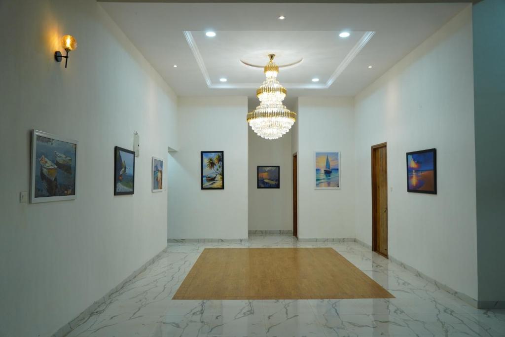 a large white room with a chandelier and paintings at Salt Water Sanctuary in Diveagar