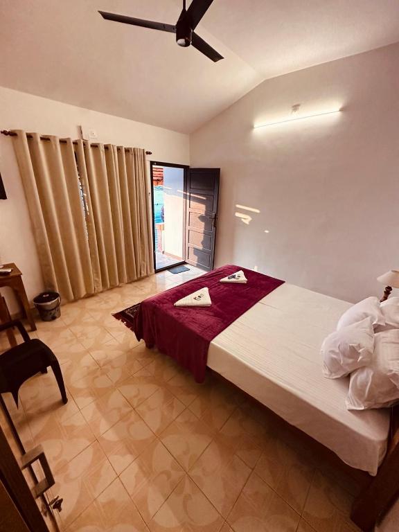 a bedroom with a large bed with a ceiling fan at The Beach Hive in Varkala