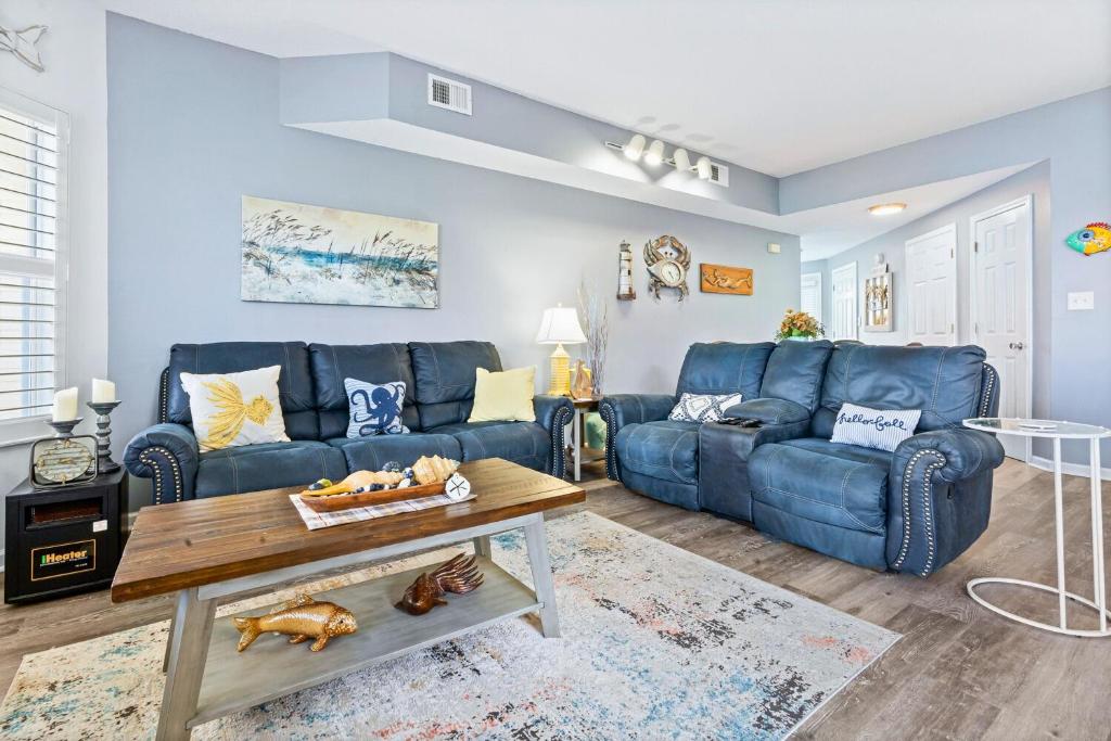un soggiorno con un divano blu e un tavolo di Hook, Wine, & Linger condo a Destin