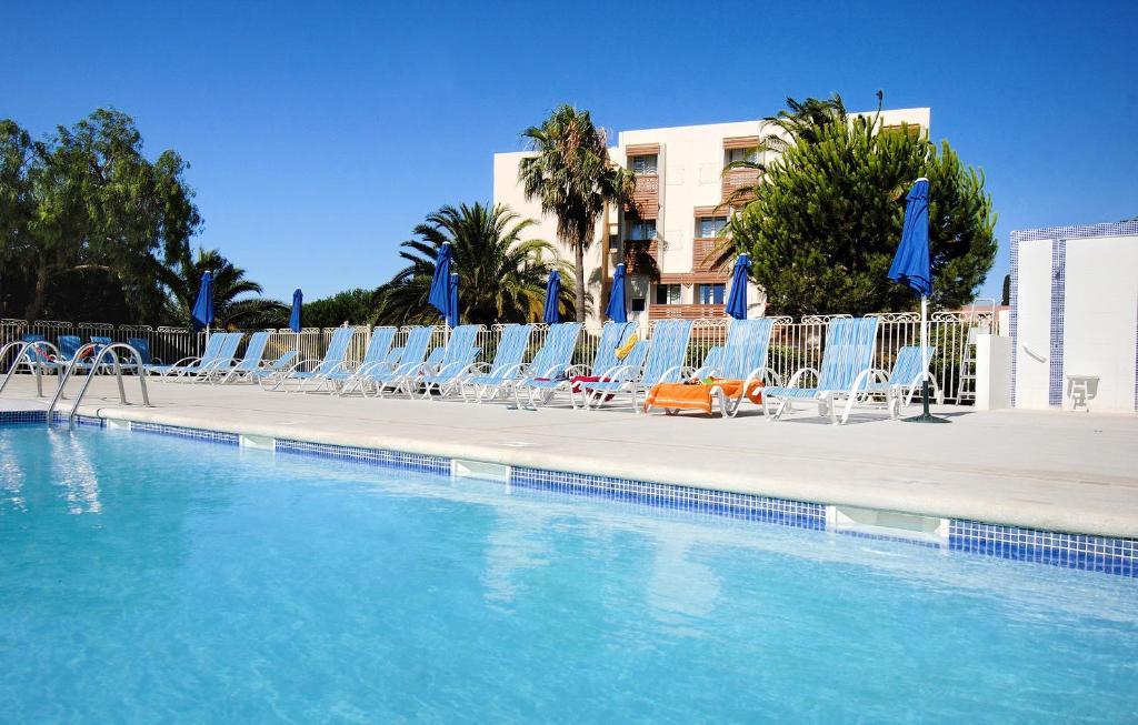 a swimming pool with lounge chairs and a swimming pool at Vacancéole - Résidence L'Ile d'Or in La Londe-les-Maures