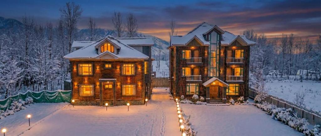 a large house with lights in the snow at The Routes Pahalgam in Kolur