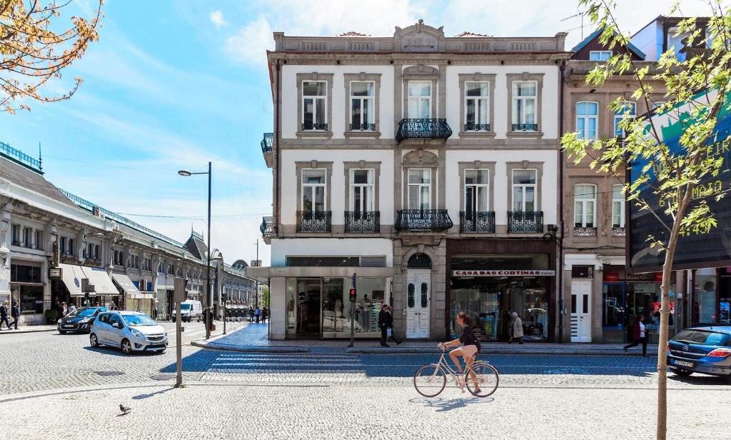 uma mulher a andar de bicicleta em frente a um edifício em BO - Fernandes Tomás no Porto