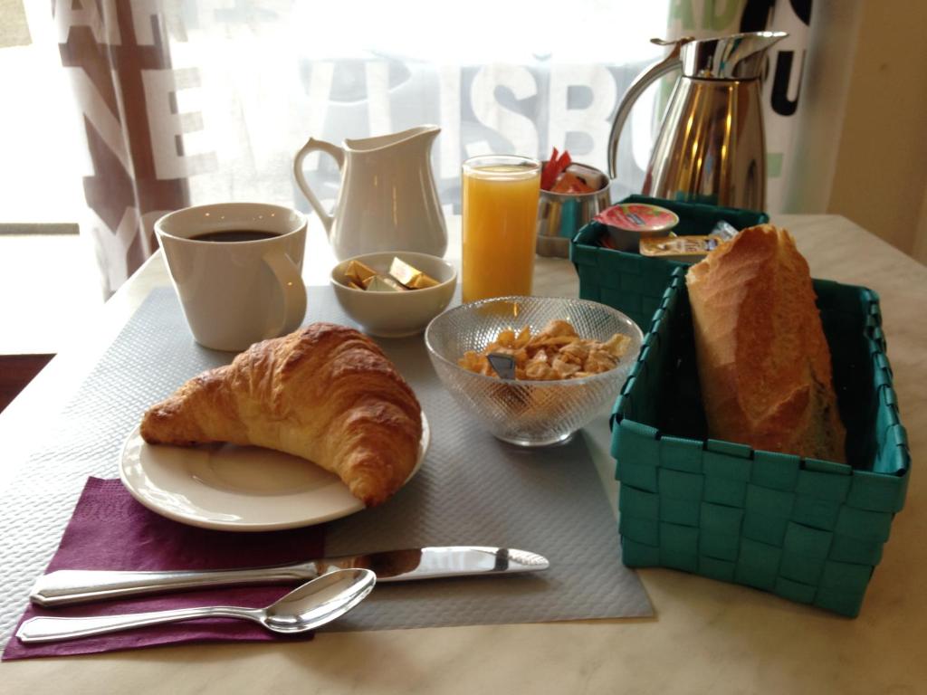 a table with a breakfast of croissants and a cup of coffee at Hotel Sandra in Vizille