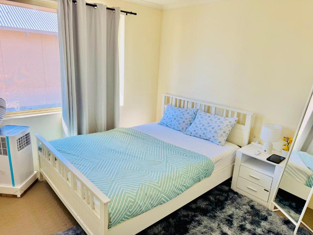 a white bedroom with a bed with a window at Affordable accommodation in Perth