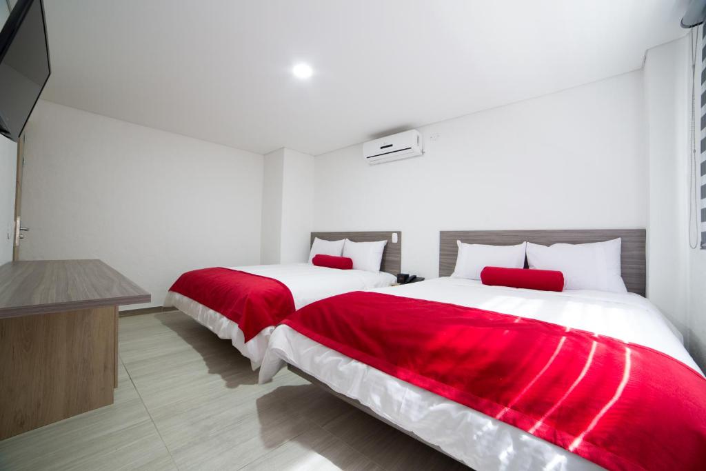 2 camas en una habitación con sábanas rojas y blancas en Hotel Med 70, en Medellín
