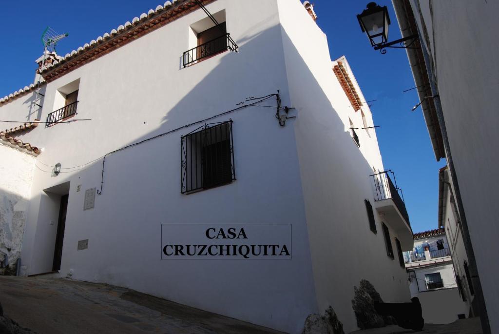 un edificio blanco con un cartel en el costado en Cruzchiquita, en Alpandeire