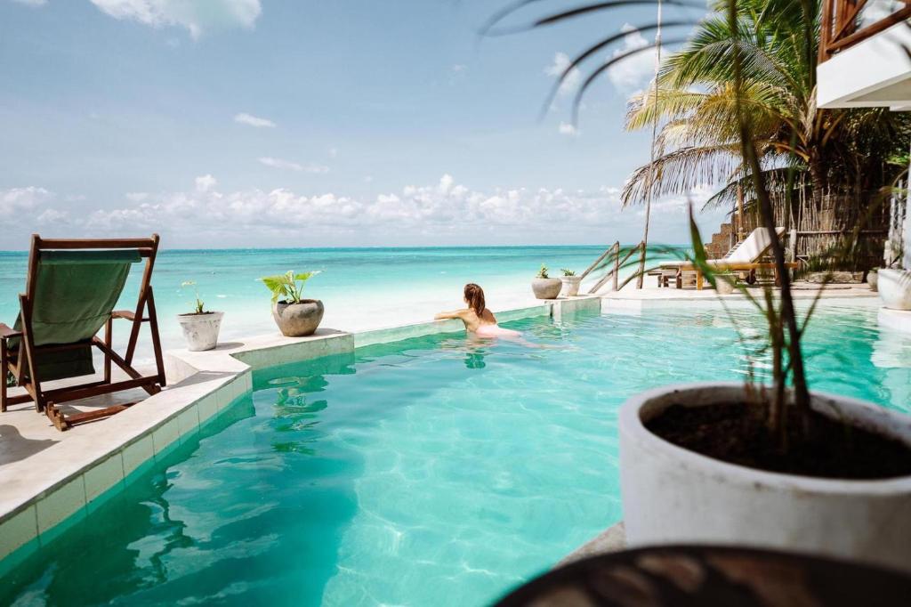 Eine Frau in einem Pool am Meer in der Unterkunft ZAN Tropical Jambiani Beach in Bwejuu