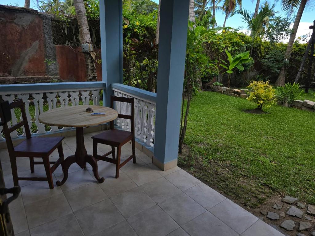 a table and two chairs on a porch with a yard at Chambre Bleu - Coco Room Nosy-Be in Nosy Be