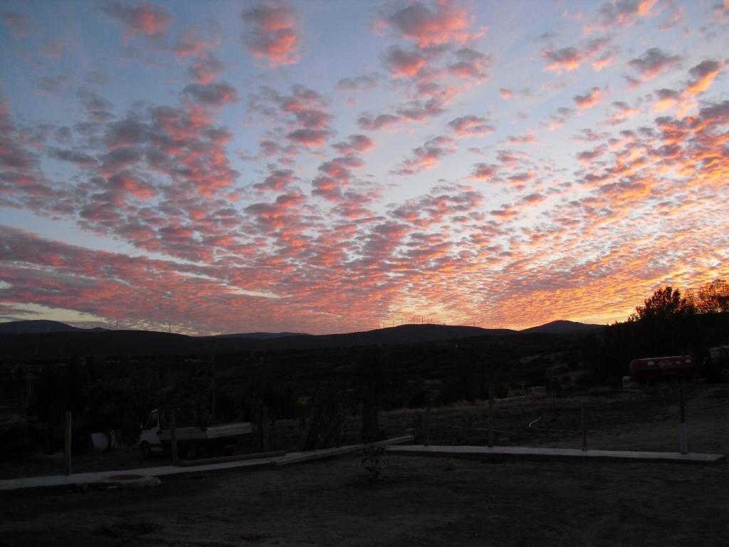 a cloudy sky at sunset with mountains in the background at La Candela in Rabanal del Camino