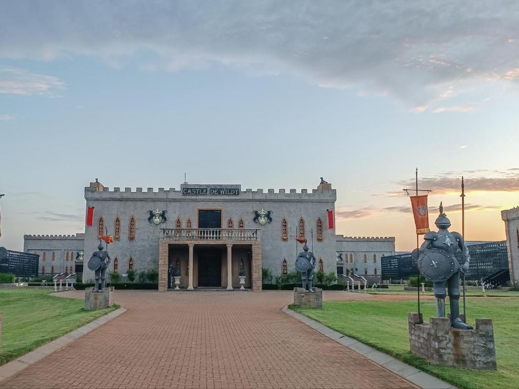 a white building with two statues in front of it at Castle de Wildt in Modimolle