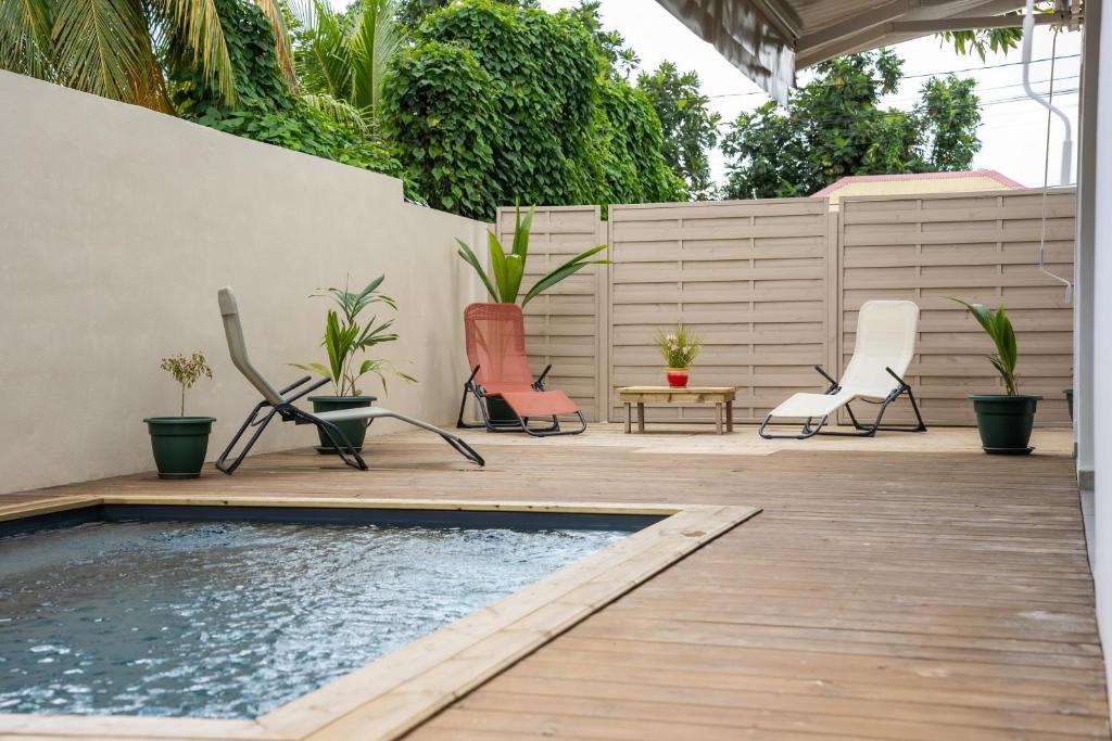 a patio with chairs and a swimming pool at Villa Le Manguier - Logement Manka, Piscine privée in Goyave