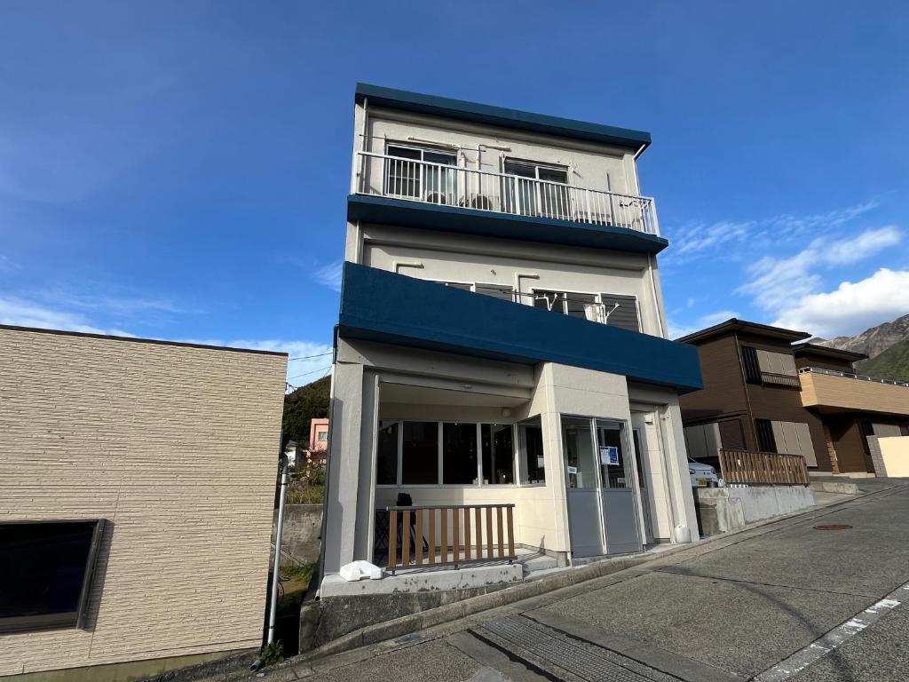 a white building with a balcony on top of it at Guesthouse&Café Deep in Kōzushima