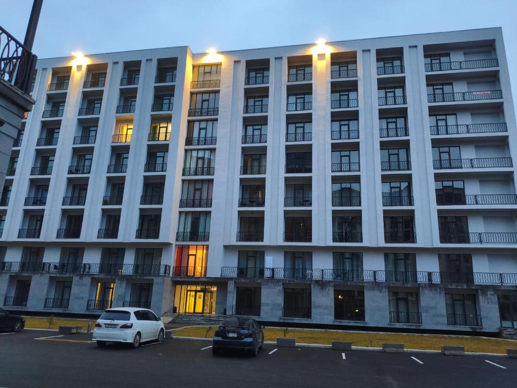 een witte auto geparkeerd op een parkeerplaats voor een gebouw bij Alvina complex in Tsachkadzor