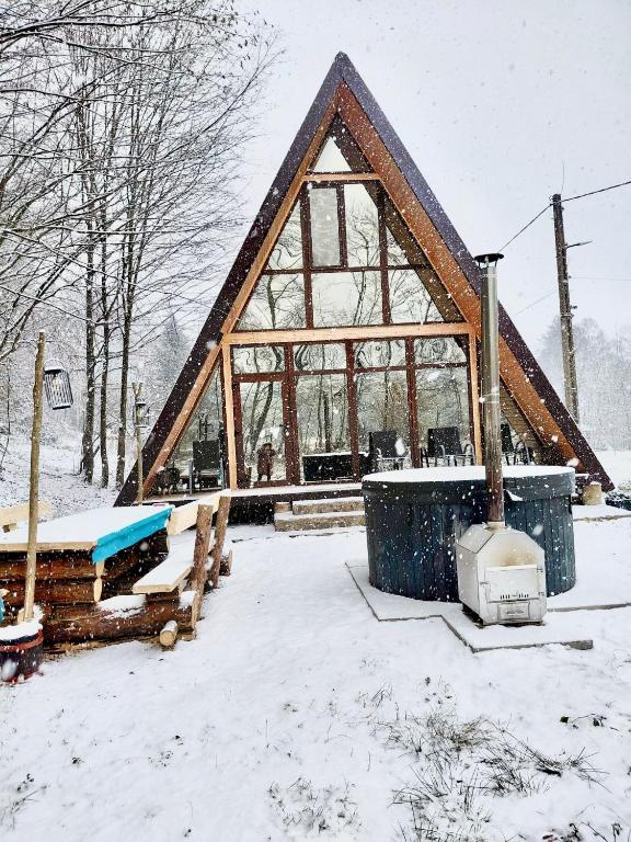 a large building with a roof in the snow at Cabana Vatra Râului in Lazuri