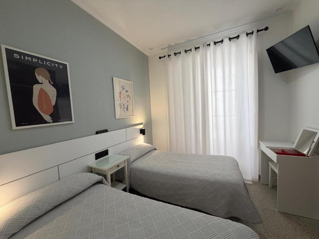 une chambre d'hôtel avec deux lits et une télévision dans l'établissement Hostal Bahía, à Cadix