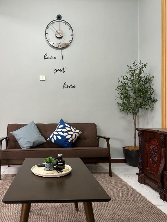 a living room with a couch and a clock on the wall at Miraana Nest in Sungai Petani