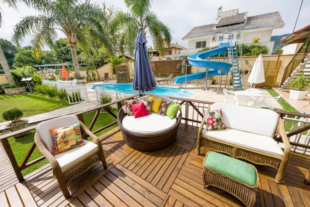 una terraza con sillas, una sombrilla y una piscina en Pousada Lozalti, en Florianópolis