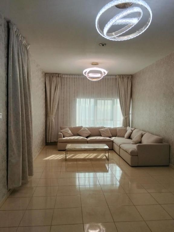 a living room with a couch and a chandelier at Orient Tower in Ajman 
