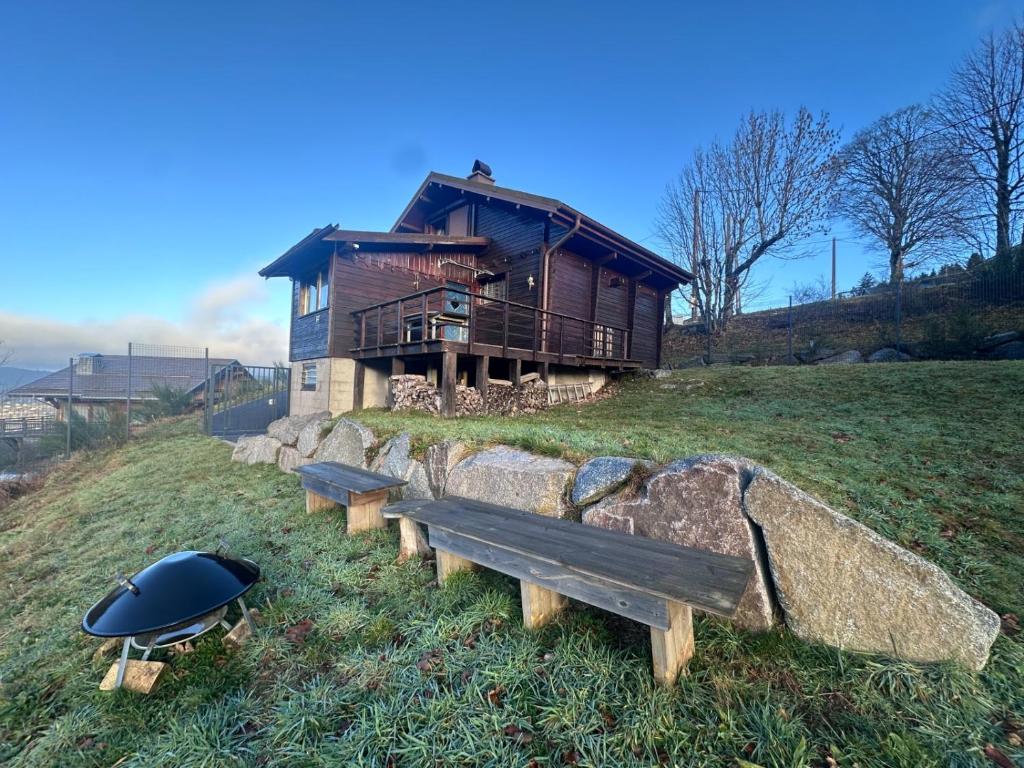 a house sitting on top of a hill with a bench at Le Chalet des 4 Chouettes in Gérardmer