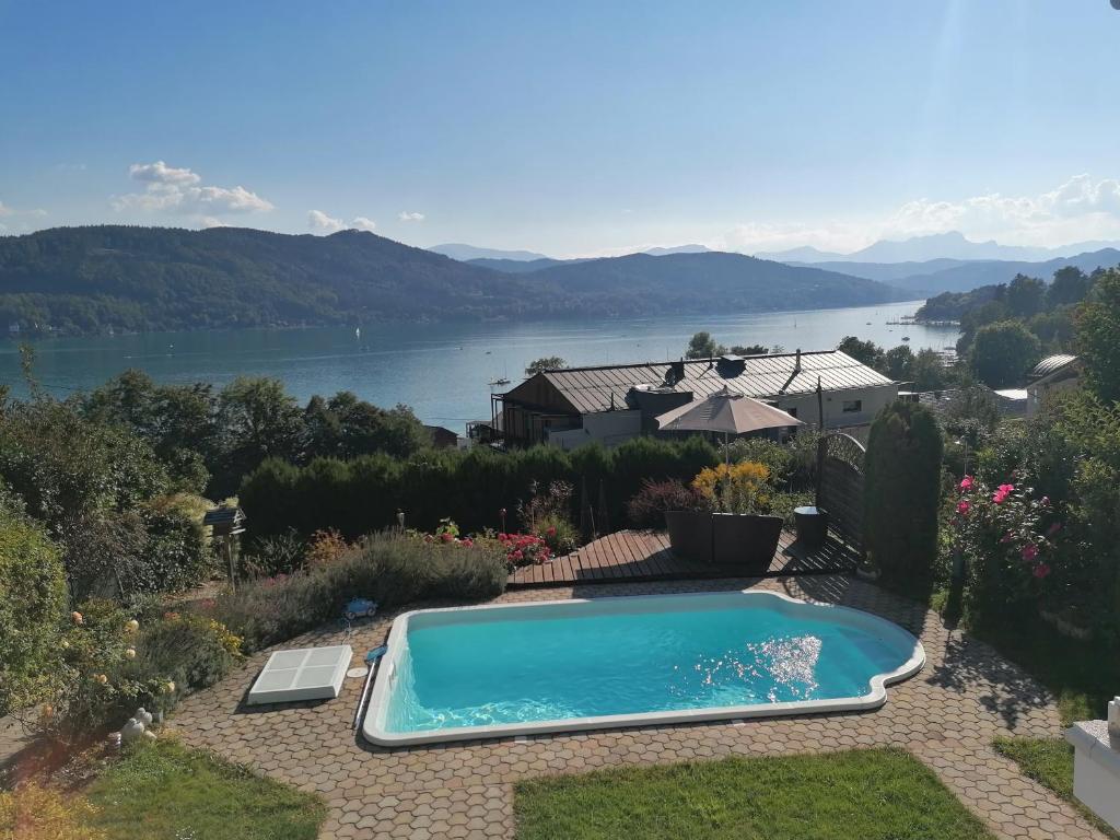 a swimming pool in a garden with a view of a lake at Holiday Apartment Krumpendorf in Krumpendorf am Wörthersee