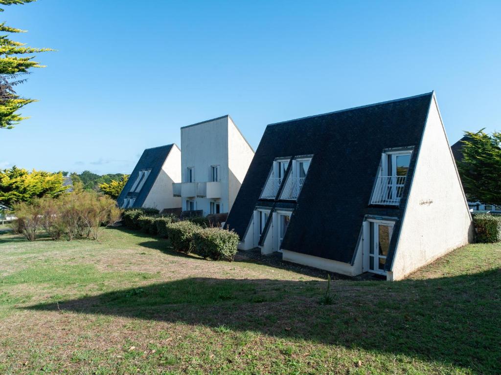 a house with a black roof on a grass field at Sud Ocean J N74 2P4 in Guidel