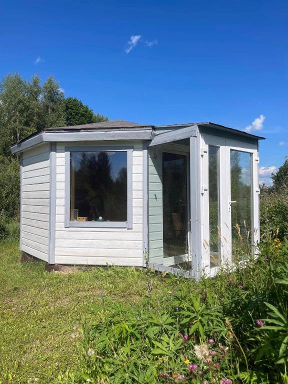 a white shed with a window in a field at namelis tyloje in Šarkiškės
