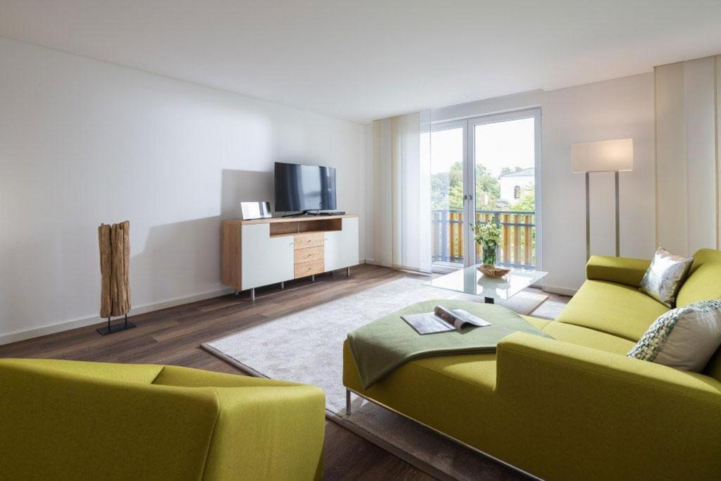 a living room with a green couch and a television at Wohnart - Fewo 6 Wohnkultur in Norderney