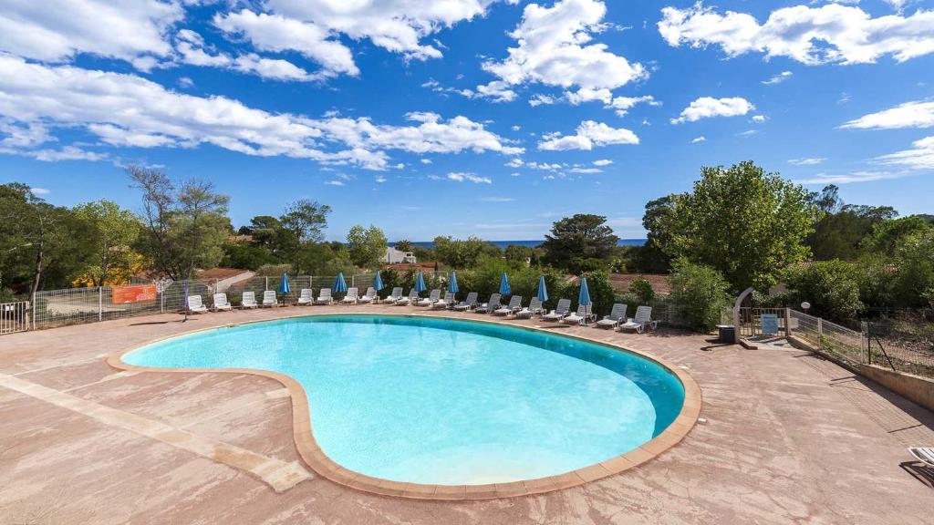 a swimming pool with chairs and umbrellas at Lisa Maria D N38 2P5 in Sari Solenzara