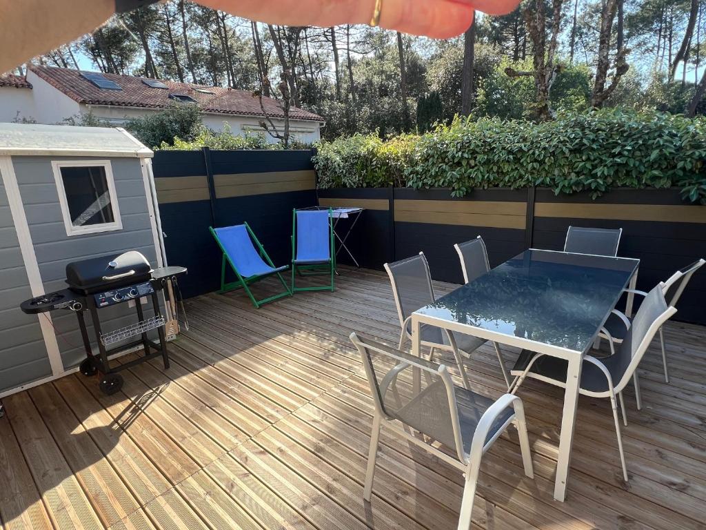 un patio avec une table, des chaises et un barbecue dans l'établissement la pinede de St georges, à Saint-Georges-de-Didonne