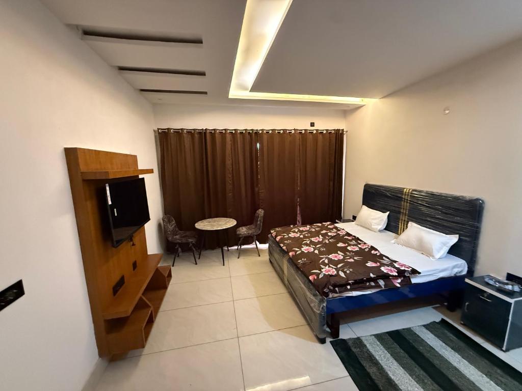 a bedroom with a bed and a tv and a table at Hotal zora in Rohtak