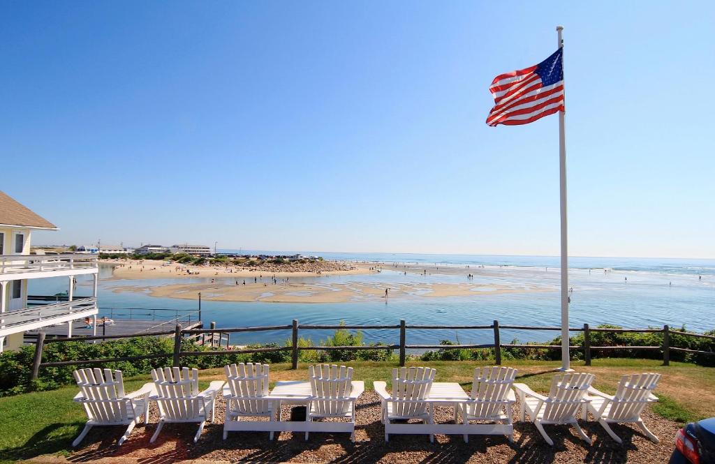 a group of white chairs and an american flag and a beach at Sea Chambers in Ogunquit