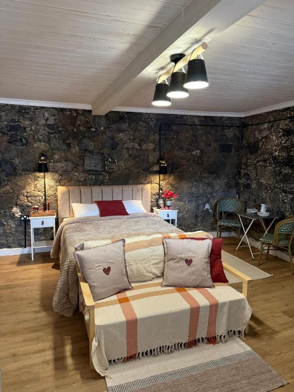 a bedroom with a bed and a stone wall at Aprosmeno House 6 in Agros