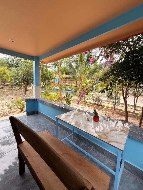 un banc en bois assis sur un porche avec une table dans l'établissement Garden Hostel Koh Rong, à Sihanoukville
