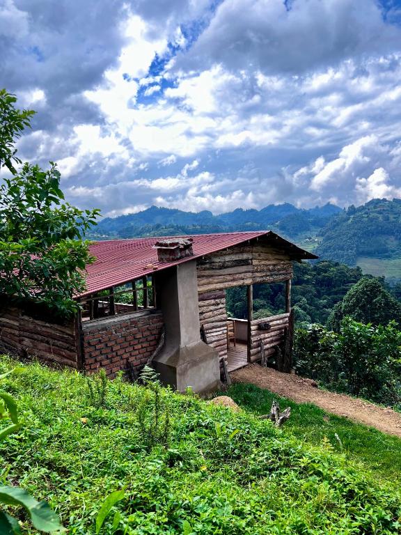 a cabin on a hill with a red roof at Migogo Gorilla Lodge in Rubuguli