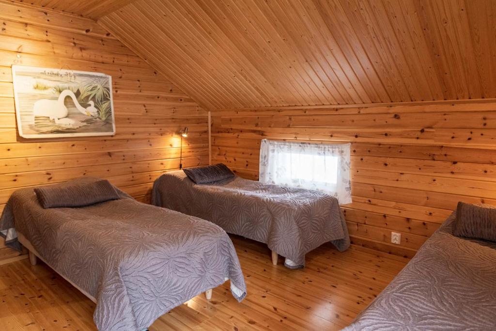 ein Schlafzimmer mit zwei Betten in einer Blockhütte in der Unterkunft Napapiirin Järvilomat in Rovaniemi