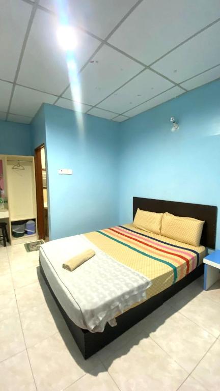 a bedroom with a bed with a blue wall at Capital O 91275 Pr Motel in Changlun