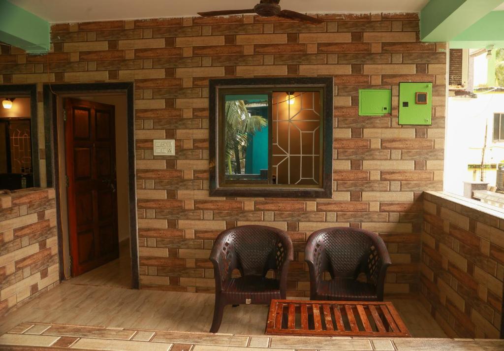 two chairs in front of a brick wall with a mirror at Dreamcatcher House & Hostel at Arambol Beach in Arambol