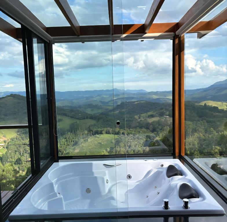 a bath tub in a room with a large window at Chalé Manacá in Sapucaí-Mirim