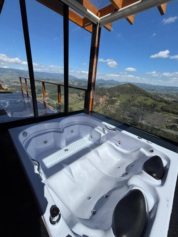 a bath tub in a room with a large window at Chalé Manacá in Sapucaí-Mirim
