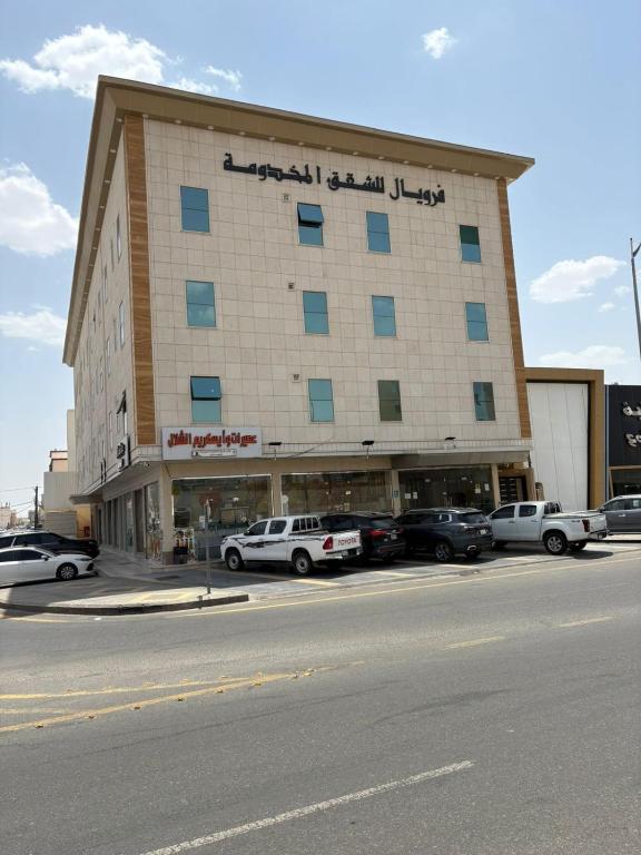 a large building with cars parked in a parking lot at فرويال للشقق المخدومة in Nughaylah