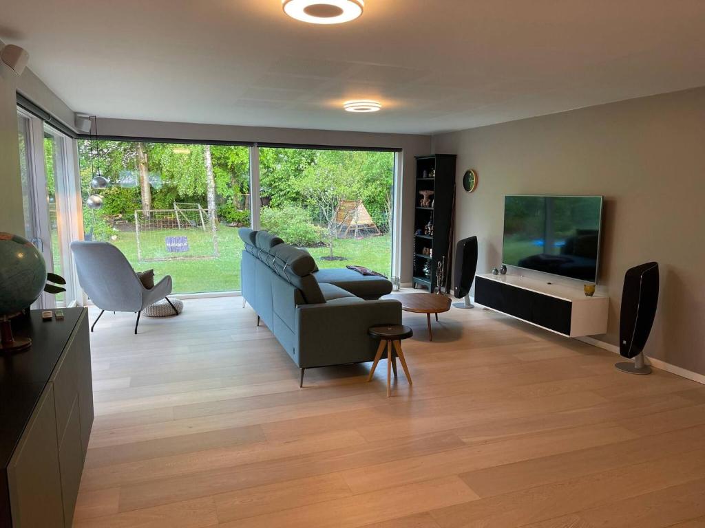 a living room with a blue couch and a tv at Skovbrynets guesthouse in Herning