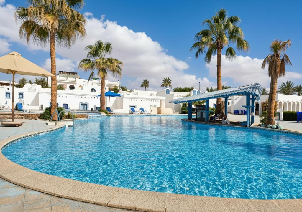une grande piscine avec des palmiers et des bâtiments blancs dans l'établissement kanabesh hotel, à Charm el-Cheikh