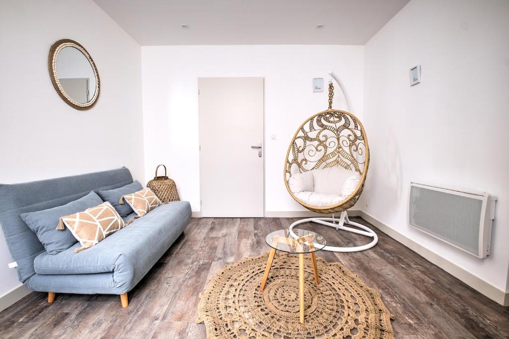 a living room with a blue couch and a mirror at les doux secrets de Bergère in Périgueux