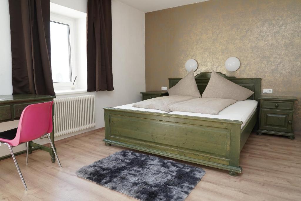 a bedroom with a green bed and a pink chair at Botenwirt - Self Check in in Spital am Pyhrn