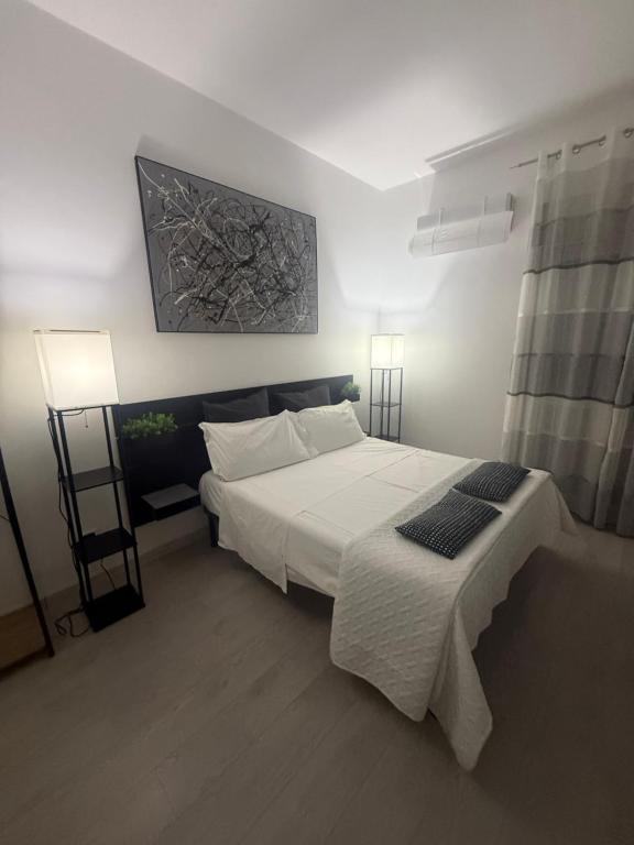 een slaapkamer met een groot wit bed met twee lampen bij Le Tre Perle in Canicattì