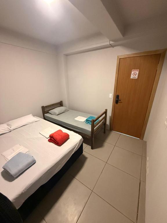 a small room with two beds and a door at Cerrado Hostel in Goiânia