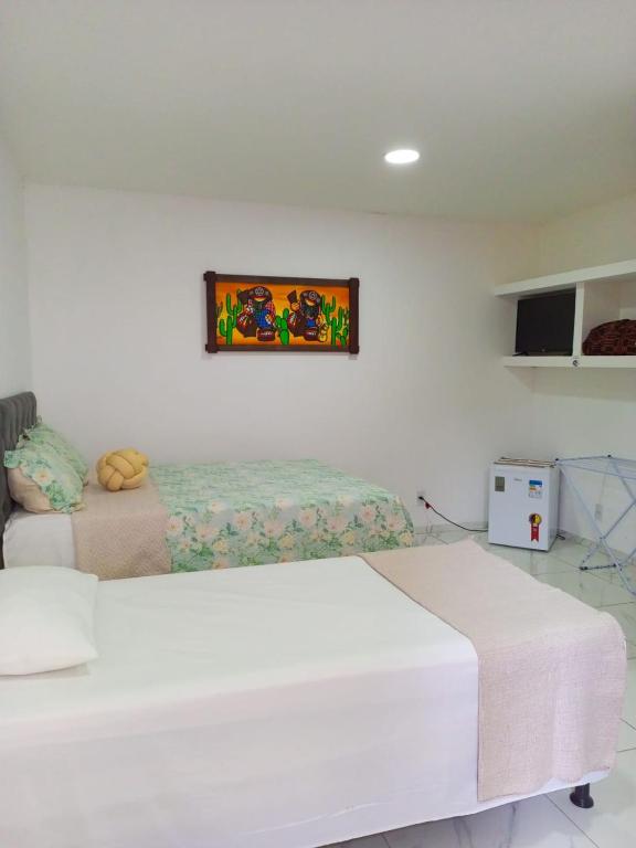 a bedroom with two beds and a tv on the wall at Kitnets Caribe Maragogi Peroba in Maragogi